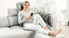 best massage chair: Woman reclining on sofa, using the Beurer MG320 massage seat pad