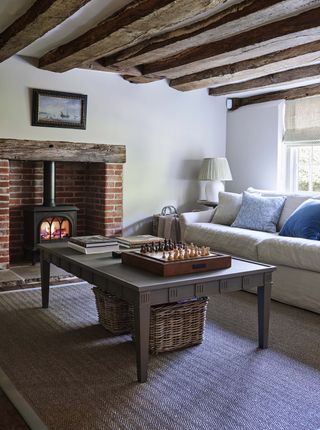 Exposed wooden beam ceiling, stone fireplace, grey coffee table