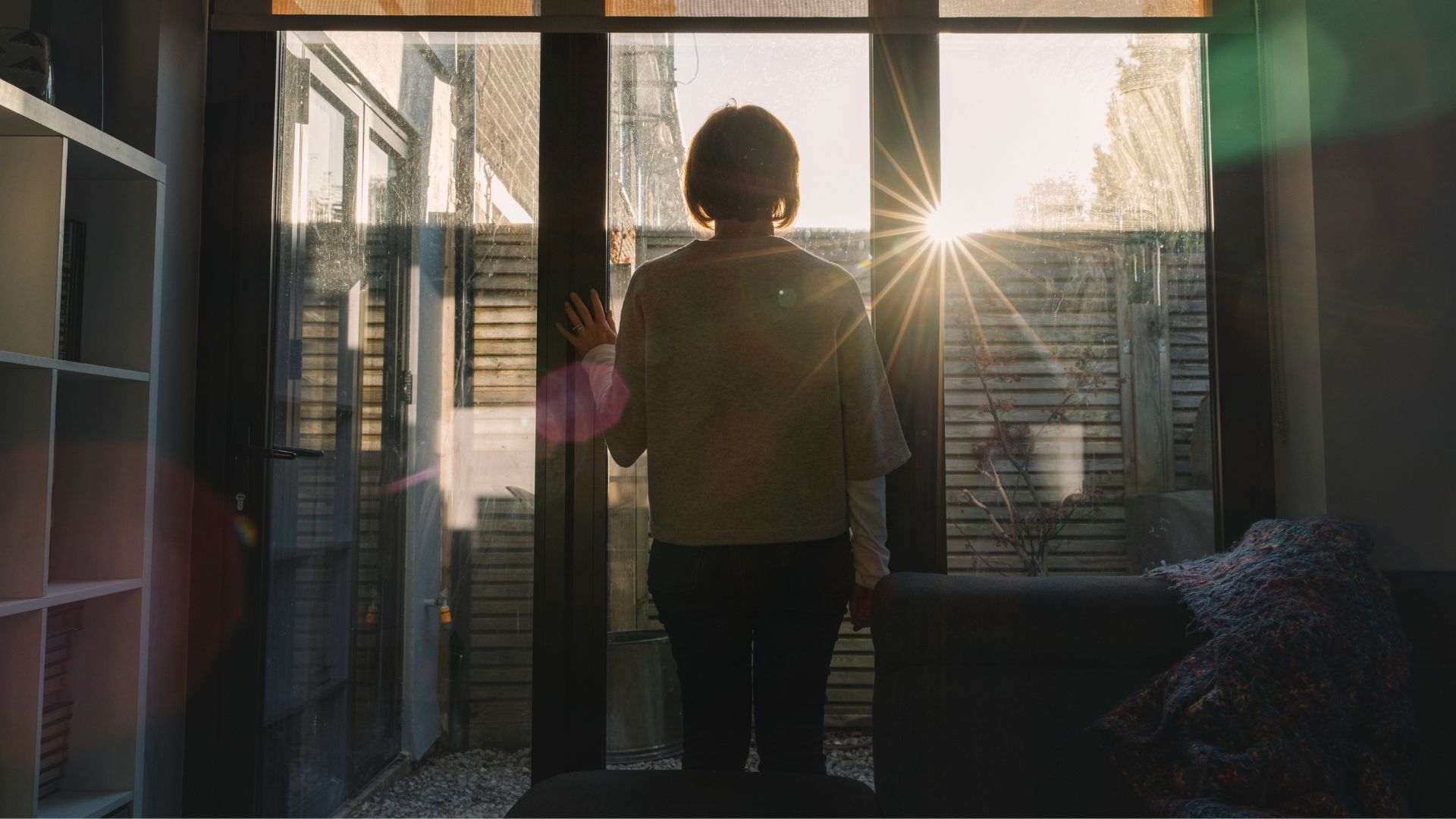 Woman looking out of the window at sun rising
