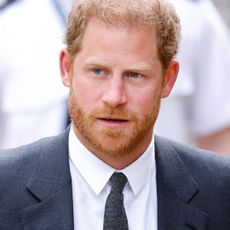 Prince Harry has red hair and a red beard and wears a navy suit and tie