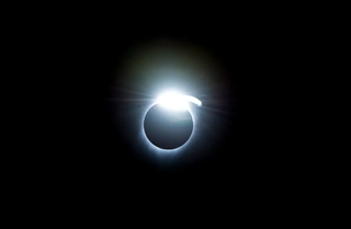 view of a solar eclipse, showing a bright ring of white light around the edge of the blocked-out sun.