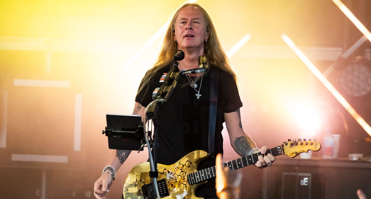 Jerry Cantrell plays his Blue Dress G&amp;L Rampage onstage against a backdrop of yellow lights 