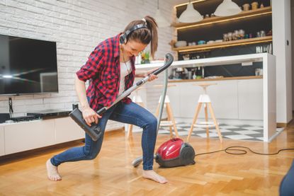 One woman, using vacuum cleaner for cleaninig her house, singing and dancing.
