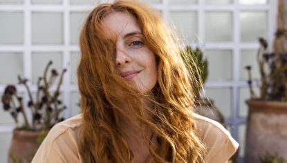Pumpkin spice hair color; Portrait of smiling redheaded young woman on terrace - stock photo