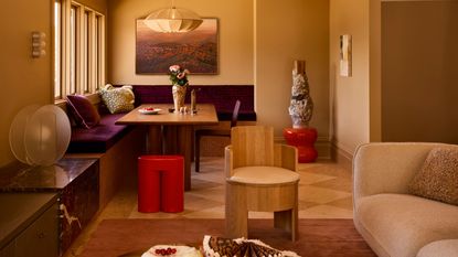 a neutral color drenched living area with a built in purple banquette seat and checkerboard flooring