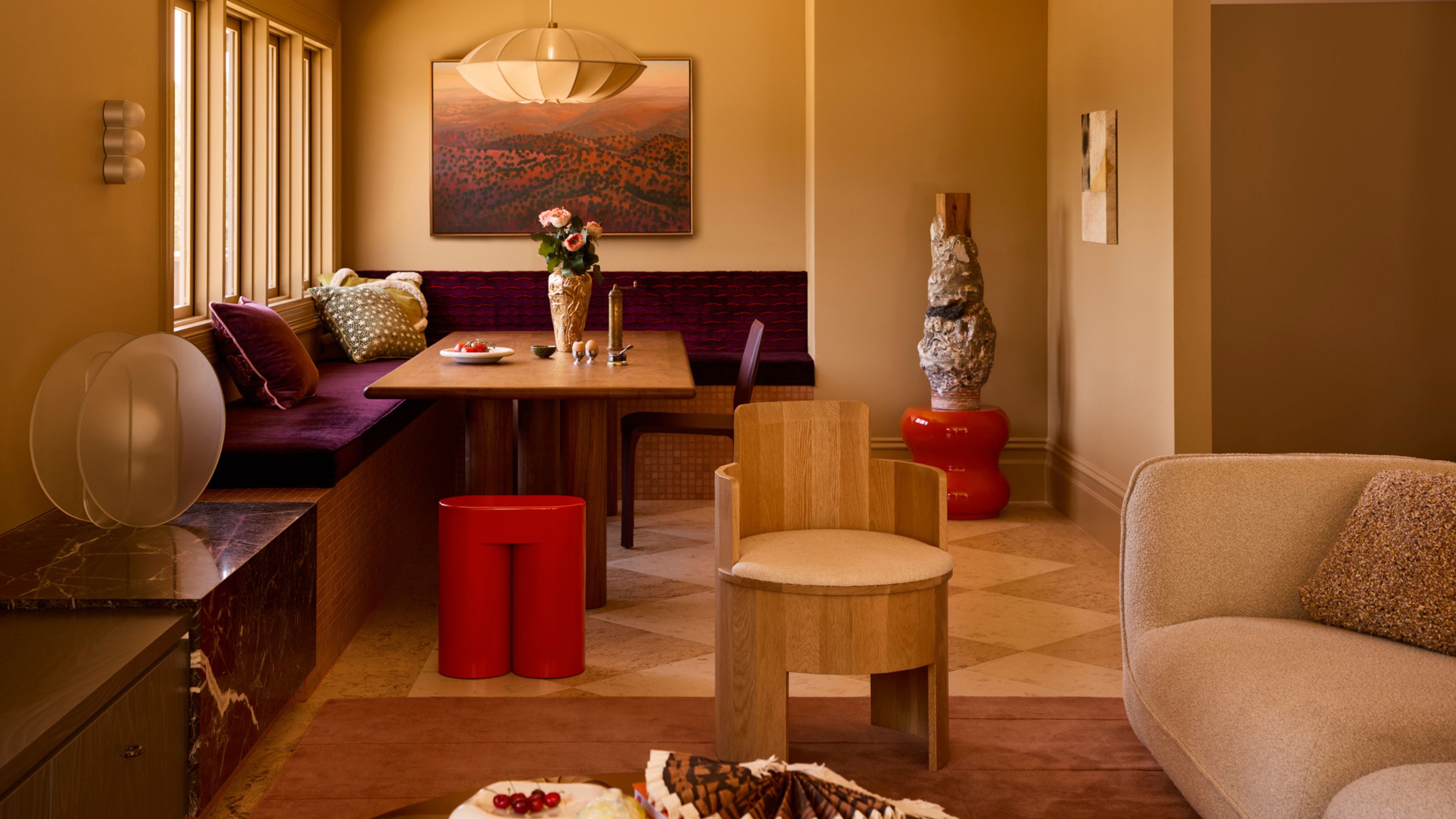 a neutral color drenched living area with a built in purple banquette seat and checkerboard flooring