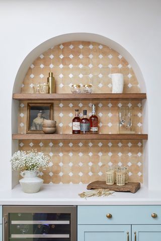 arched alcove with open shelves and terracotta tiled backsplash in kitchen with white worktop