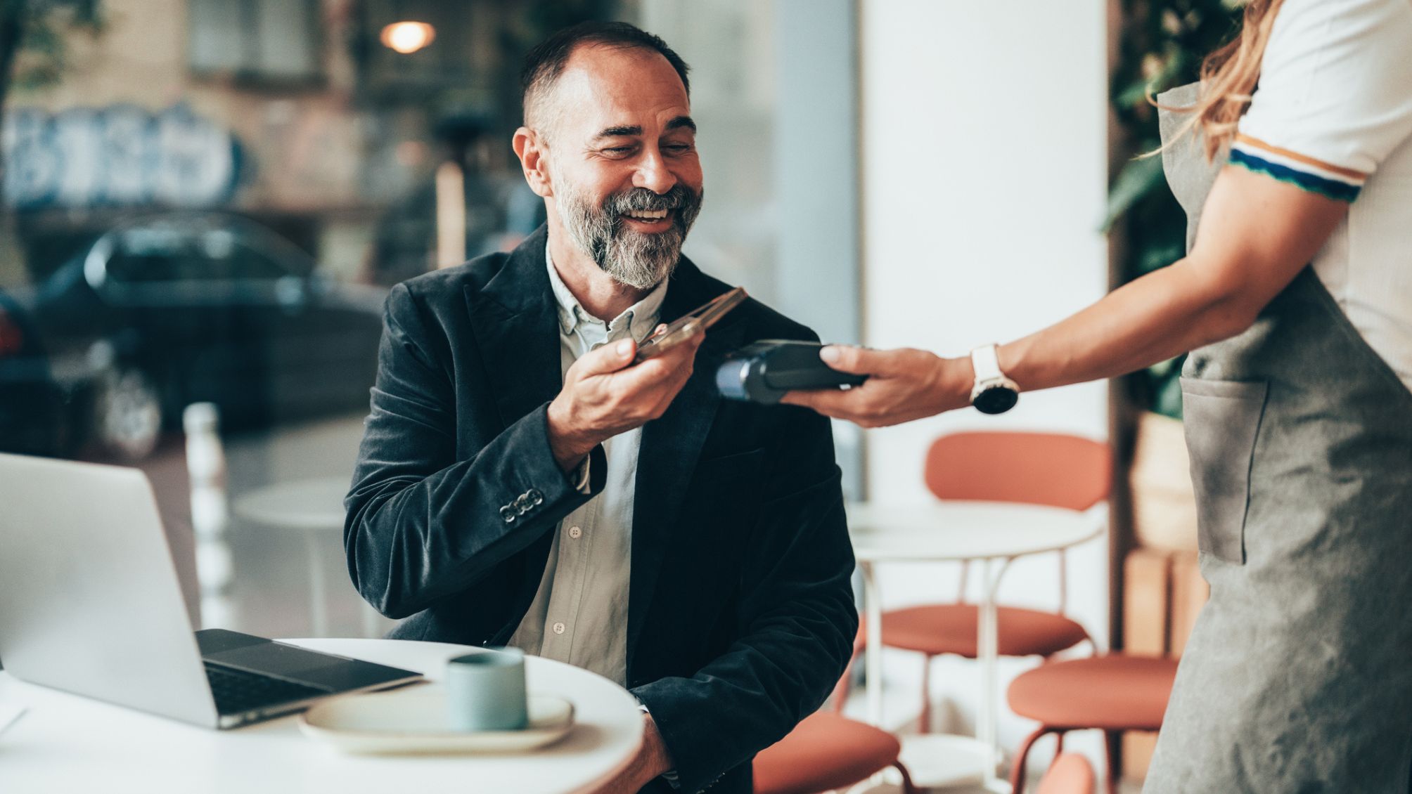 A man tapping to pay at a coffee shop. 
