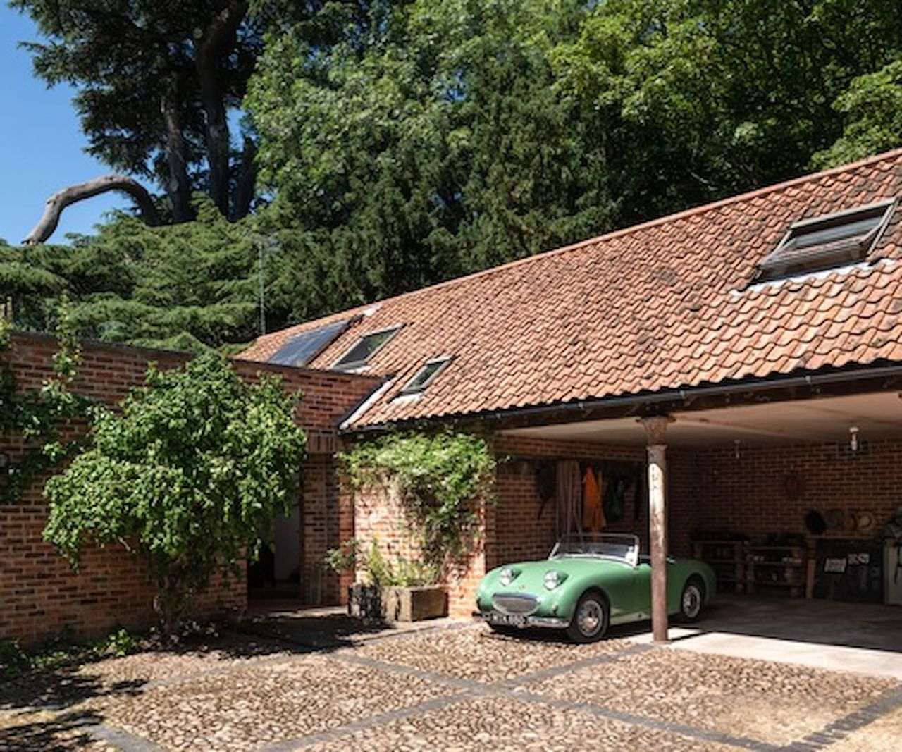 A garage with clay tiled roof next to a walled garden