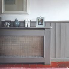 A hallway with a grey radiator cover and a mirror