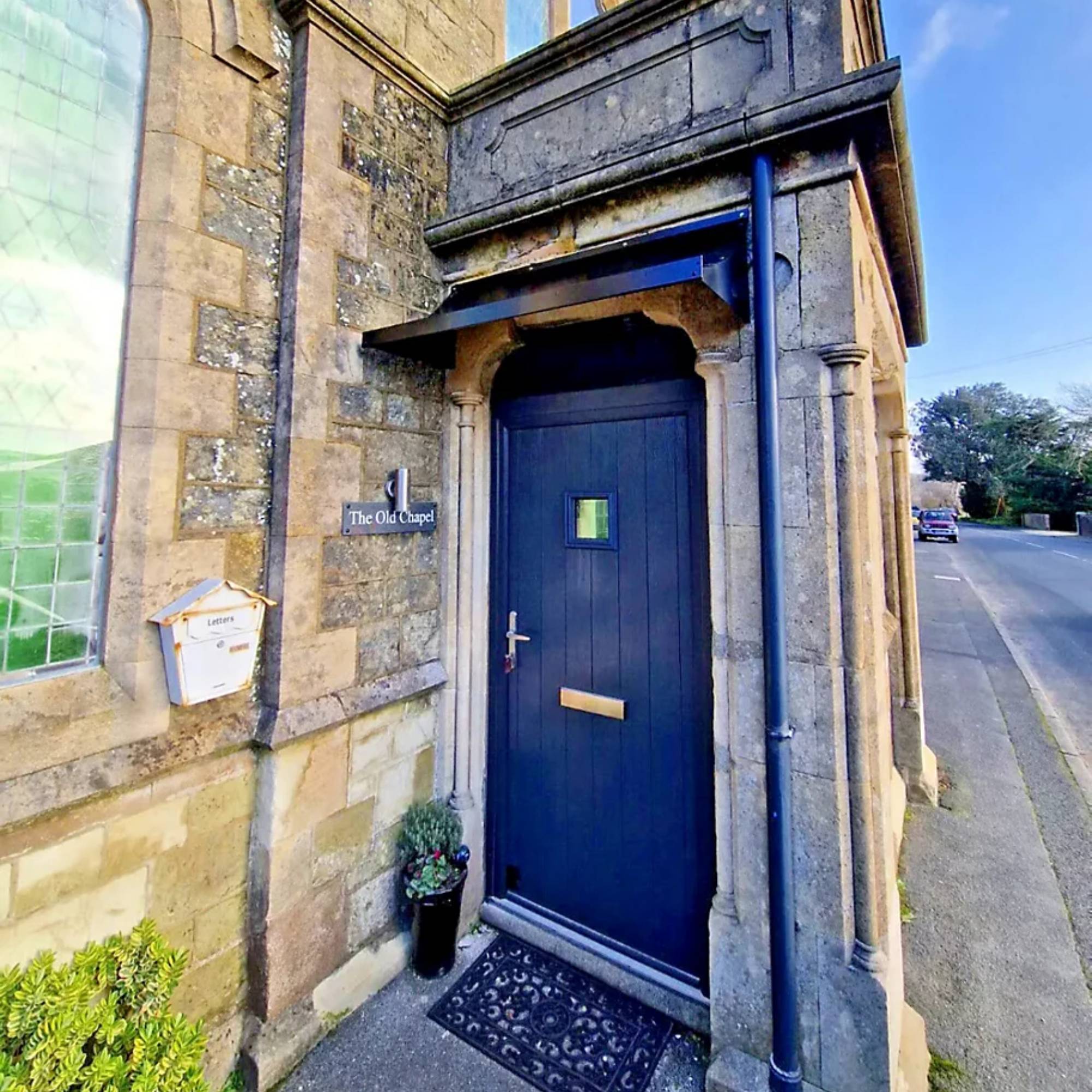 steel canopy above a black front door on stone historic house