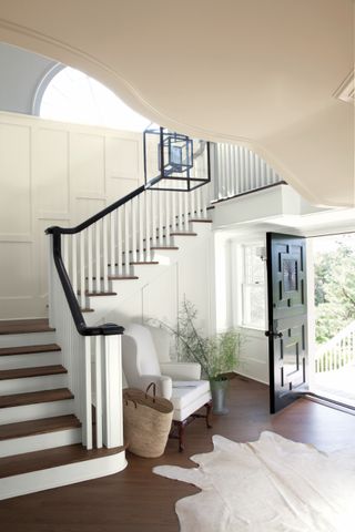 staircase with wood steps, off-white walls with panelling and black rail and spindles