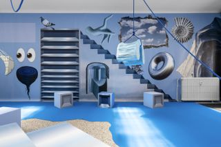 Marsèll Paradise - a blue wall with objects such as a pair of eyes, a tornado, a pigeon, a hand, a shell, a sky, a wheel, a radiator, a set of shelves.