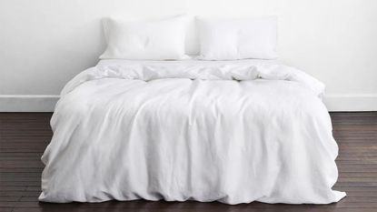 Washing bed sheets - white bedding in plain room