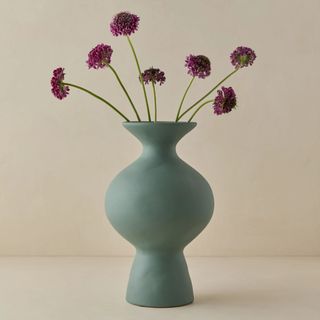 teal sculptural vase with purple flowers