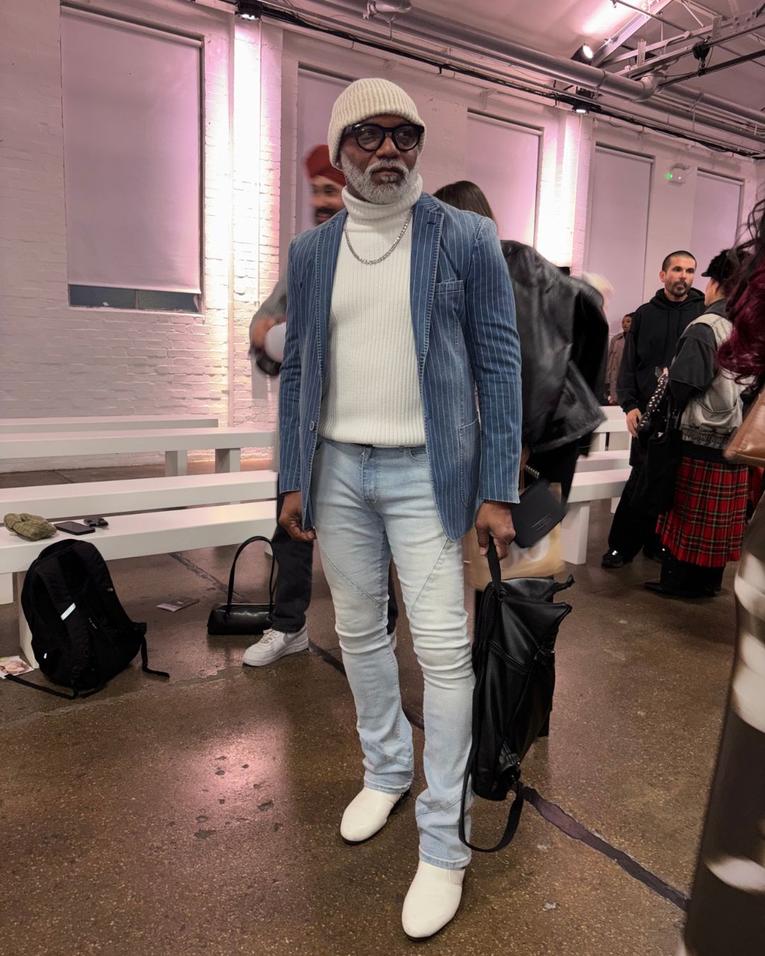 an image of Mark, a photographer and fashionista at London Fashion Week, wearing skinny light denim jeans, a ribbed white turtleneck jumper, and a darker denim pinstripe blazer