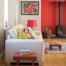 living room with wooden burning stove white sofa and red lamp