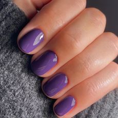 A close-up shot of a bold, glossy purple manicure