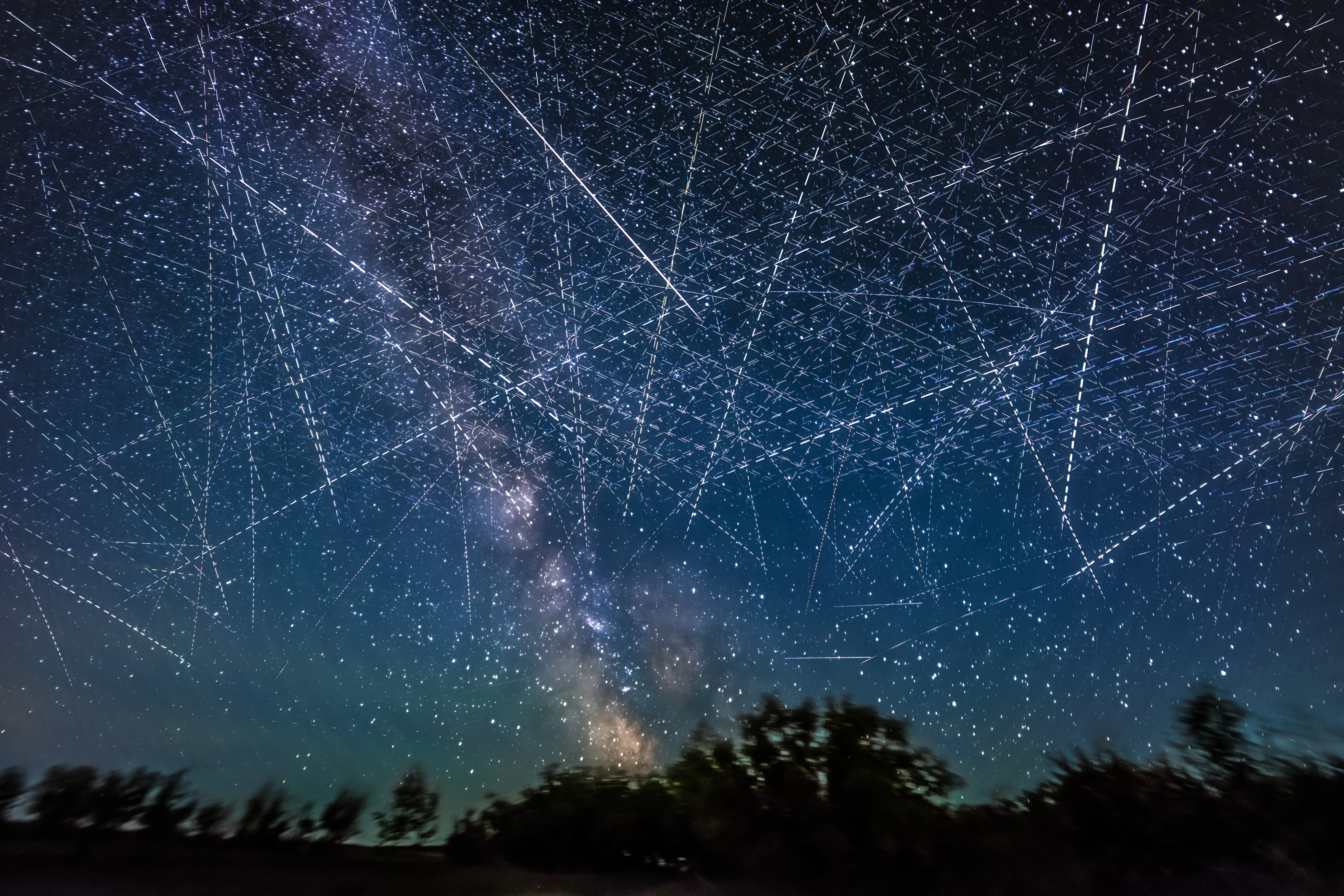 This depicts the satellite-filled sky that is now a reality and getting more crowded every week! This adds together exposures taken over just 30 minutes on an early June night when, from my latitude of 51° N satellites even in low Earth orbit are lit all night by sunlight. Many of the parallel streaks heading generally horizontal west to east (right to left) may be from groups of SpaceX Starlinks. Others traveling vertically north-south are more likely from Earth observation satellites. There is at least one natural streak in the image — a meteor at centre, caught by chance on one frame. It appears as a colored and tapered streak.