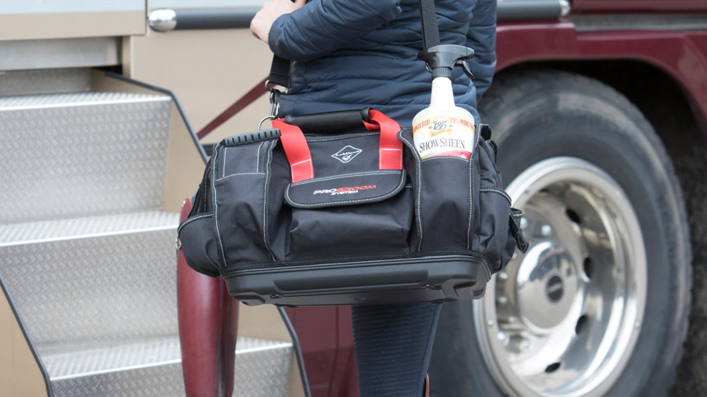Rider carrying horse grooming bag up lorry steps
