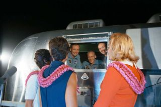After returning home from the moon, the Apollo 11 crew is greeted by their wives while they are in the Mobile Quarantine Facility.