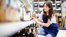 A teenage clerk arranges items on a grocery store shelf.
