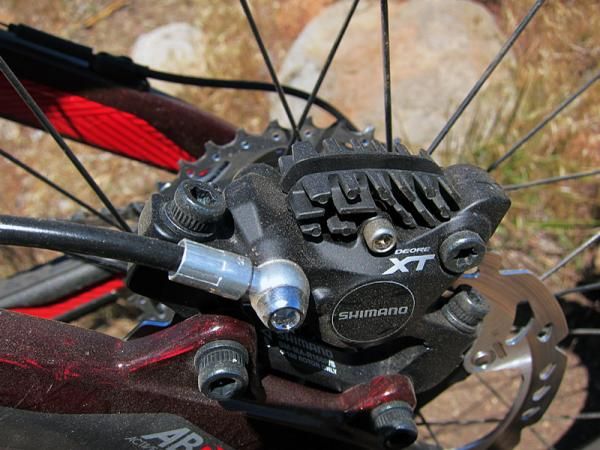 Shimano's revamped Deore XT brake caliper uses a two-piece forged aluminum body with more advanced heat management features that include 22mm-diameter ceramic pistons and finned brake pads.