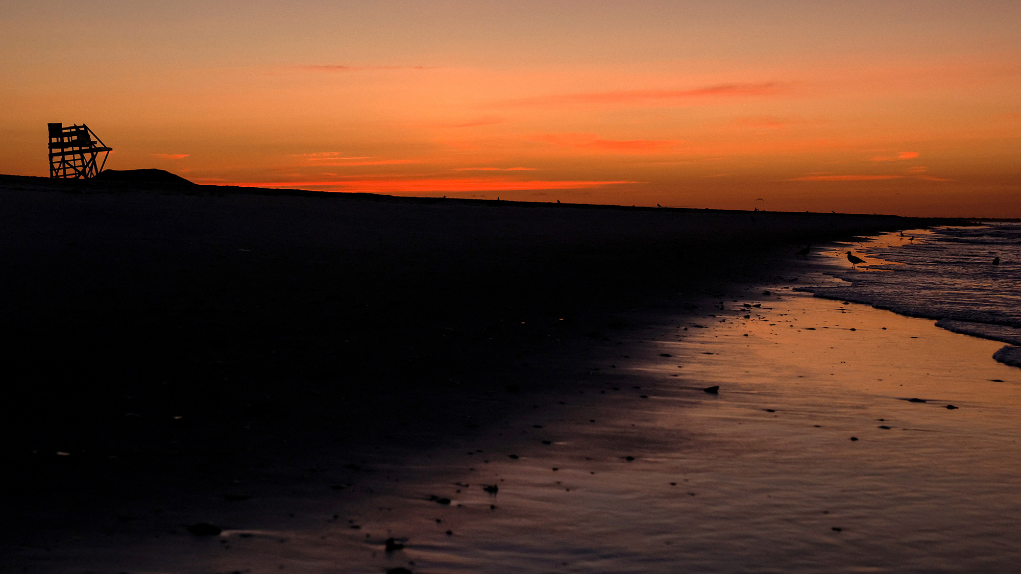 Lifeguard chairs stand stacked at sunrise, marking the end of summer supervision, at Lido Beach, New York