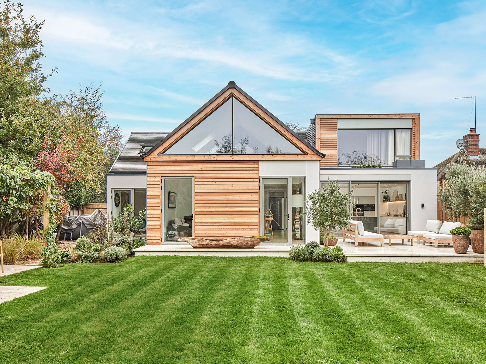 extended and renovated house with a large garden with lawned area and a patio with outdoor sofas 