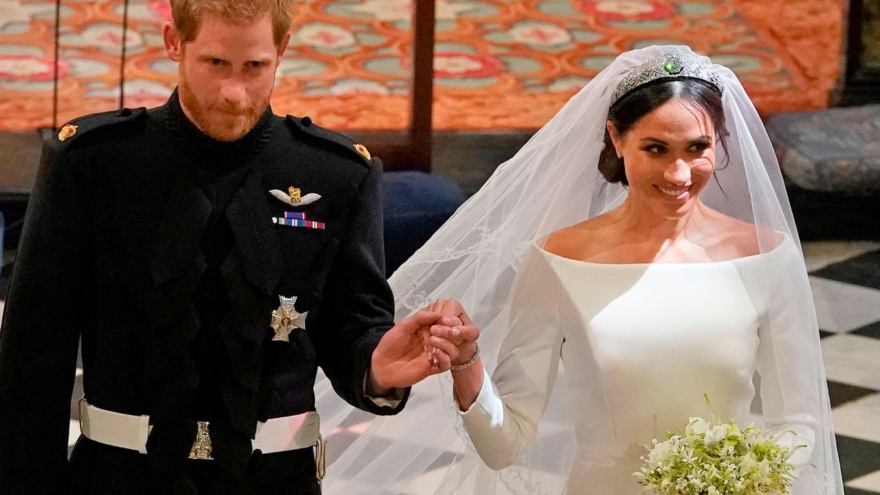 Prince Harry wears army uniform to marry Meghan Markle, who is wearing a long sleeved white gown and floor length veil