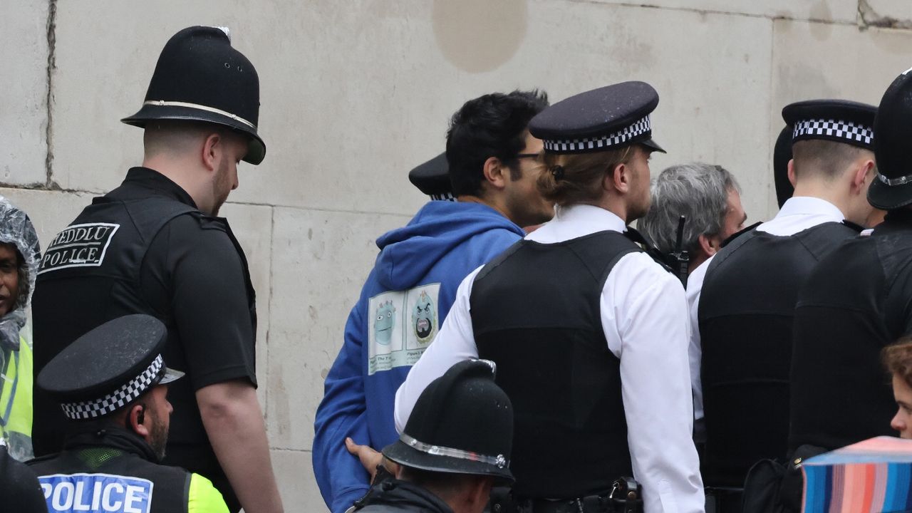 A man is arrested and led away by Police officers during the Coronation of King Charles III