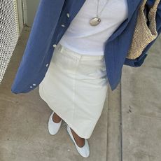 @deborabrosa wears a pair of white ballet flats, a cream denim skirt and a blue shirt