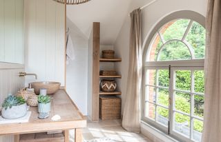 bathroom with large arched window and linen curtains druce