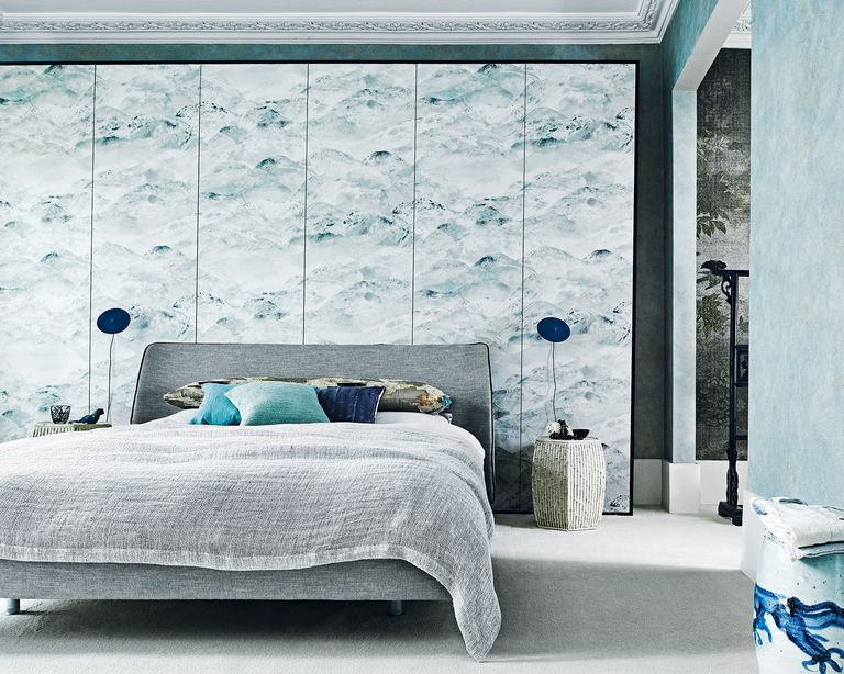 An example of bedroom trends 2021 showing a grey bed against a decorative blue wall