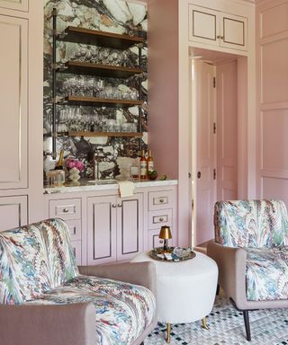 Pale pink sitting room with a marble home bar and cocktail chairs in ornate velvet