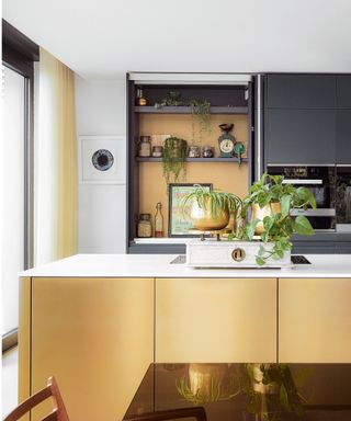 Gold kitchen island with marble worktop and plants as decoration