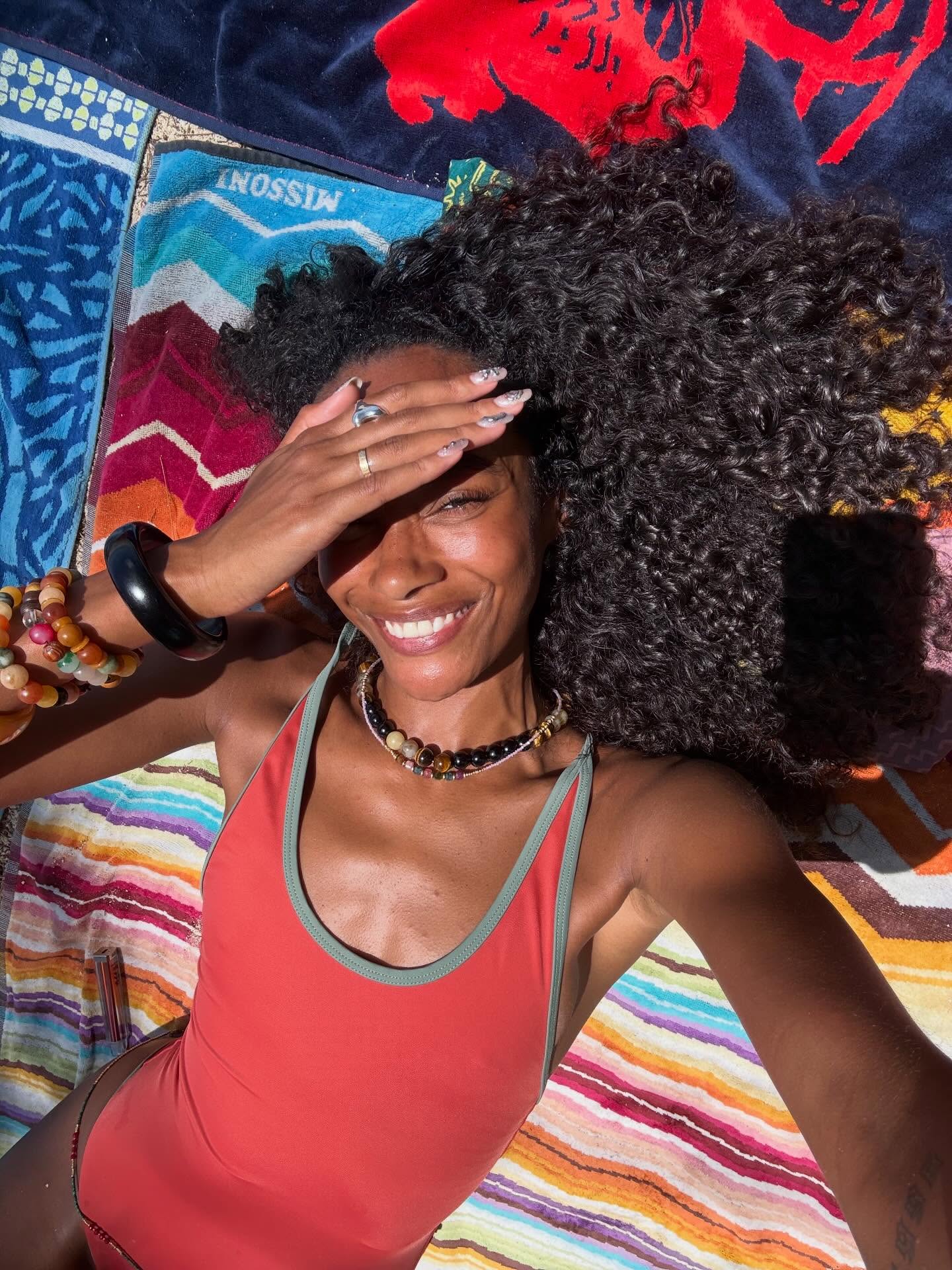 A woman with glowing skin in a bathing suit on a towel.