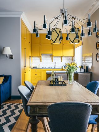 small, bright yellow kitchen with contemporary feel and impressive light fitting, example of effective kitchen planning by delightfull