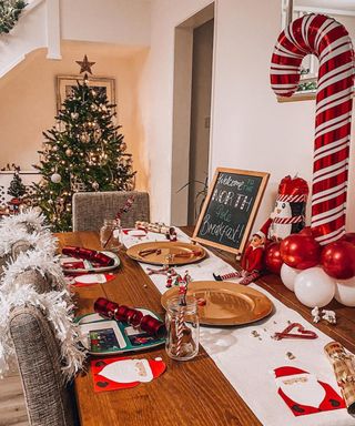 A North Pole themed table with elves and chalkboard signage on dining table with Christmas tree in background