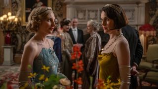 Lady Edith and Lady Mary dressed up at a party in Downton Abbey: The Grand Finale, staring at each other