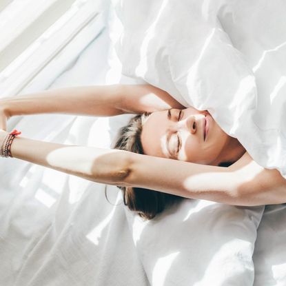 A woman stretching in bed in the morning