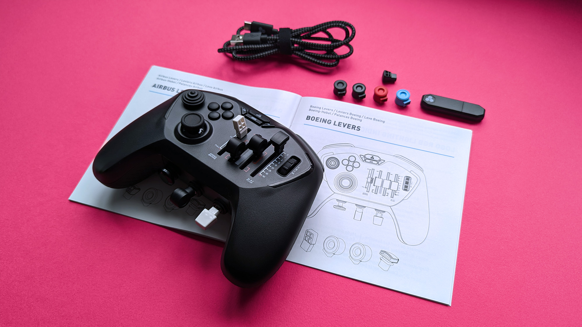 Honeycomb Aeronautical Echo Aviation Controller unboxed on a magenta cardstock background, highlighting the instruction manual and accessories