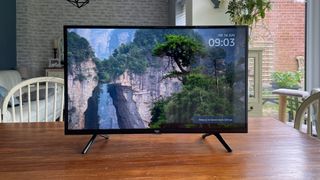 Amazon Fire电视32英寸2系列（HD32N200U）32英寸电视正面安装在木制桌子上，屏幕上有戏剧性的场景
