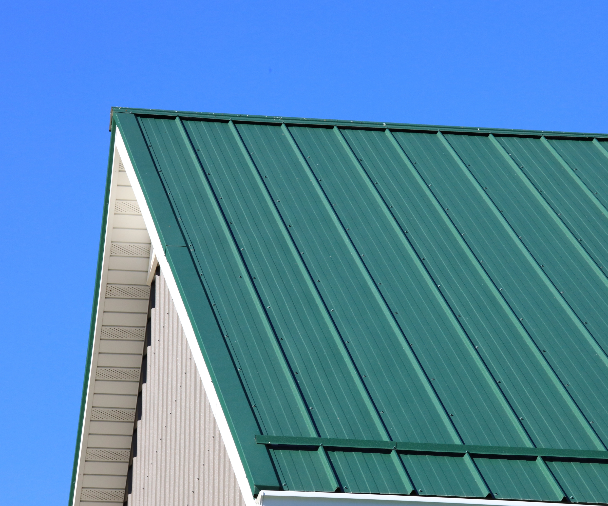 Green metal roofing with bright blue cloudless sky background