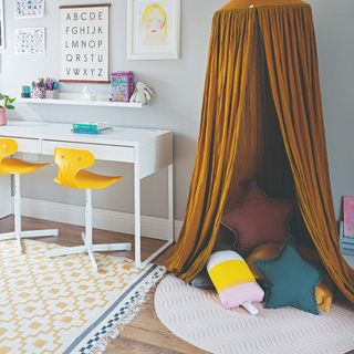 A kids' reading nook with differently shaped cushions and a curtain