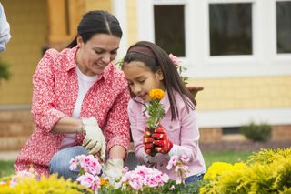 A happy mother and daughter planting flowers in the garden together.