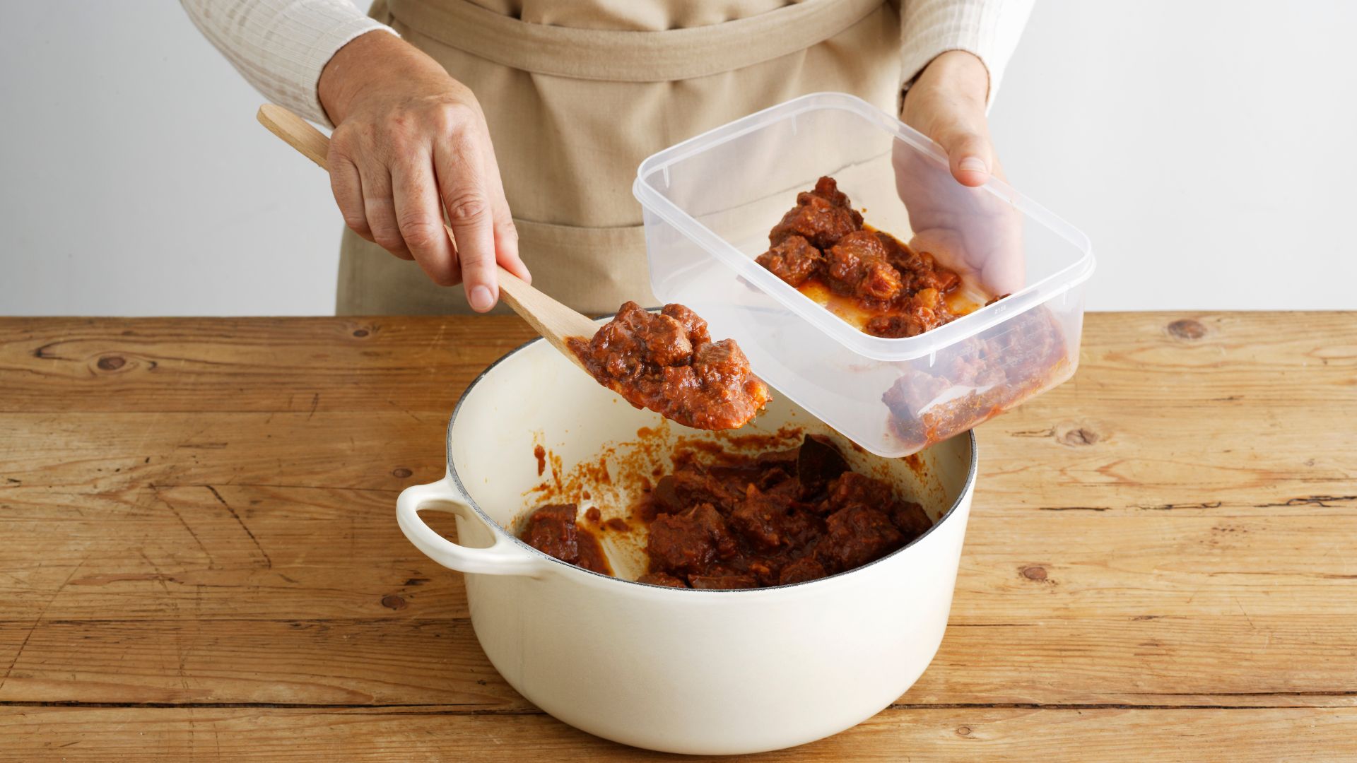 Woman putting stew into a tupperware container