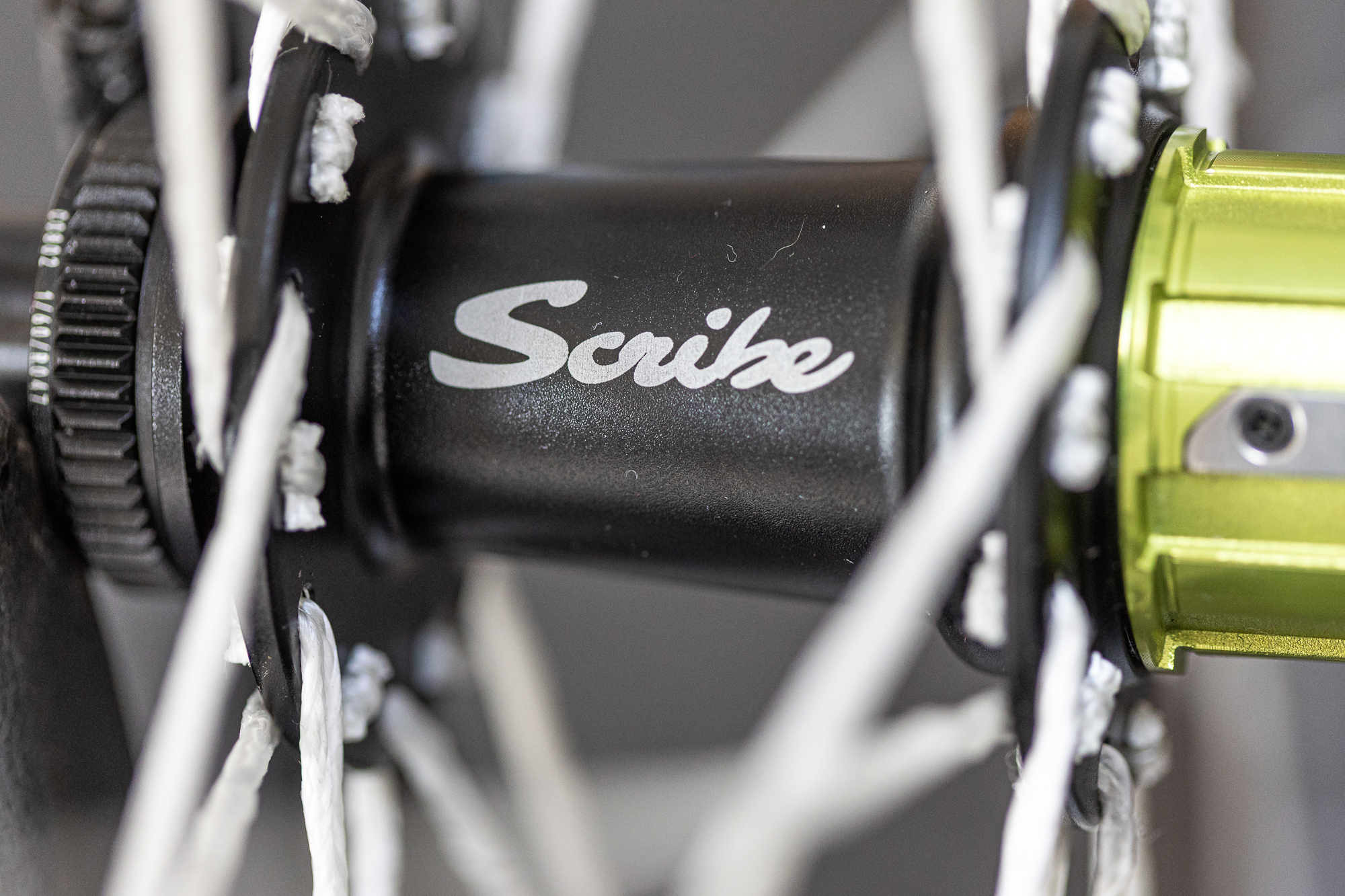 close up of a black rear hub with the brand 'Scribe' on it and white Dyneema spokes