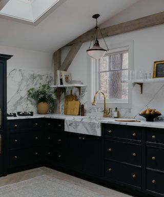 Black kitchen with marble countertop and wooden beams
