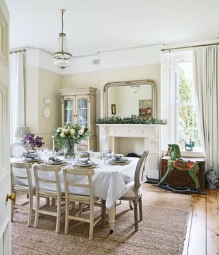 traditional-style dining room at Christmas with high ceiling chandelier and flowers on table and rocking horse